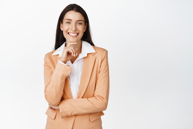 Femme d'affaires réussie souriant regardant heureux portant costume d'affaires debout sur fond blanc