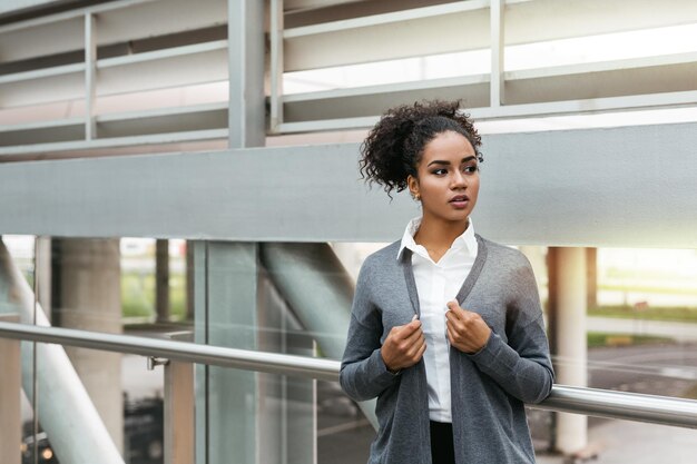 Femme d'affaires sérieuse debout dans le terminal de l'aéroport à la recherche de suite