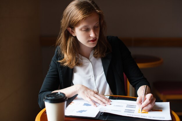 Femme d&#39;affaires sérieuse travaillant avec des papiers au café