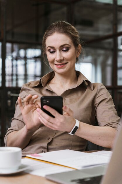 Femme d'affaires Smiley à l'aide de son smartphone lors d'une réunion