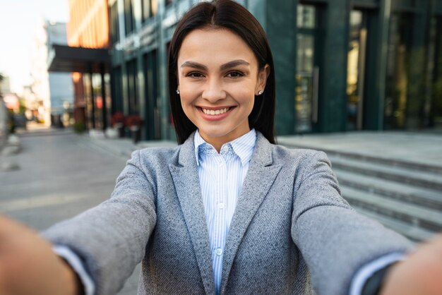 Femme d'affaires Smiley prenant un selfie dans la ville