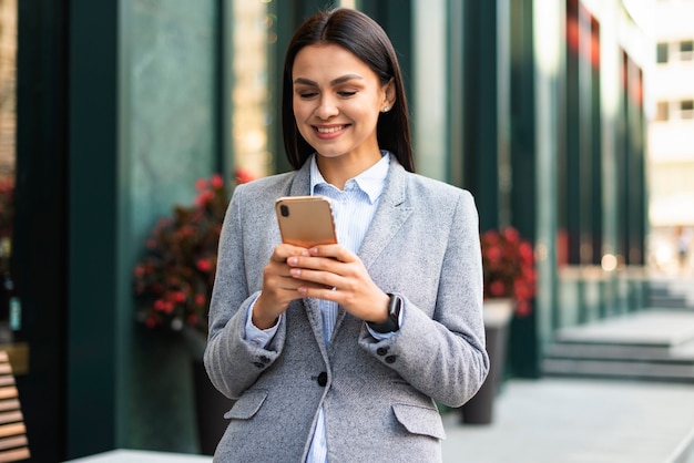 Photo gratuite femme d'affaires smiley avec smartphone à l'extérieur