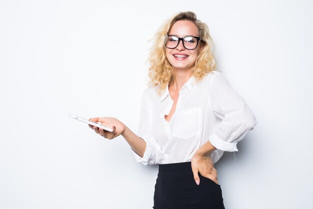 Femme d'affaires souriante à l'aide de smartphone sur un mur gris. Porter en chemise bleue et lunettes.