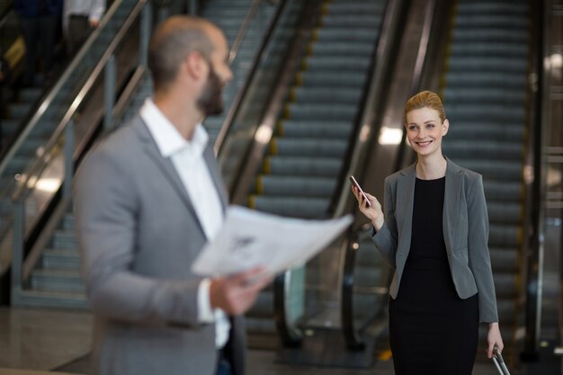 Femme d'affaires souriante interagissant avec l'homme d'affaires dans la zone d'attente