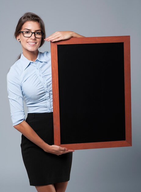 Femme d'affaires souriante montrant le tableau noir vide