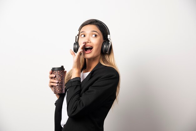 Femme d'affaires souriante avec tasse et casque.