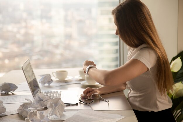 Femme d&#39;affaires surmenée regardant une montre, vérifiant qu&#39;il est temps de respecter les délais