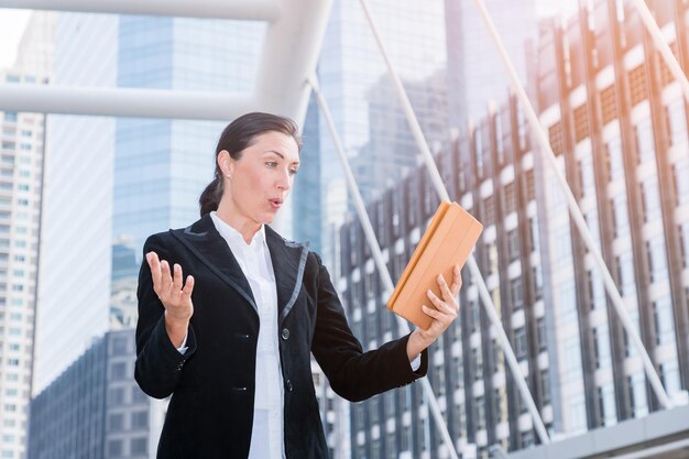 Femme d'affaires surprenante utilisant une tablette en ville