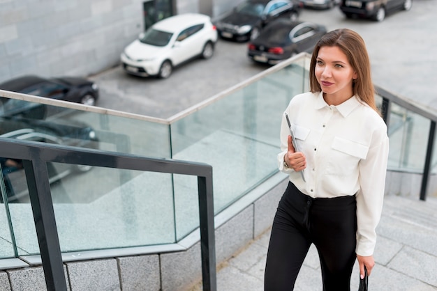 Photo gratuite femme d'affaires avec une tablette dans la rue