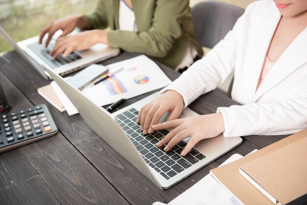 Femme d'affaires tapant sur ordinateur portable chez les femmes au travail travaillant dans le clavier de main de bureau à domicile.
