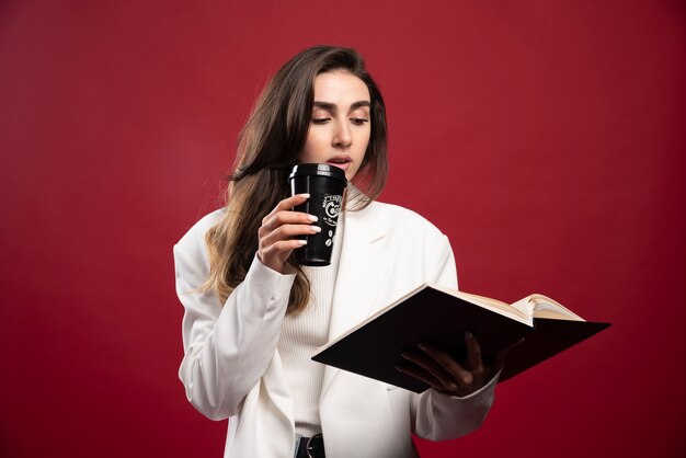 Femme d'affaires avec une tasse à la recherche sur un ordinateur portable