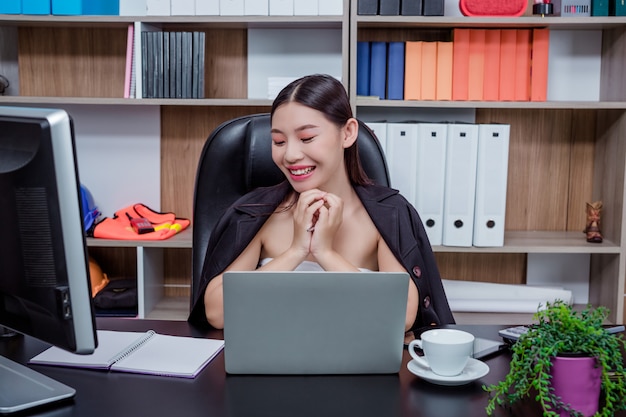 Femme d'affaires travaillant au bureau avec un sourire en position assise.