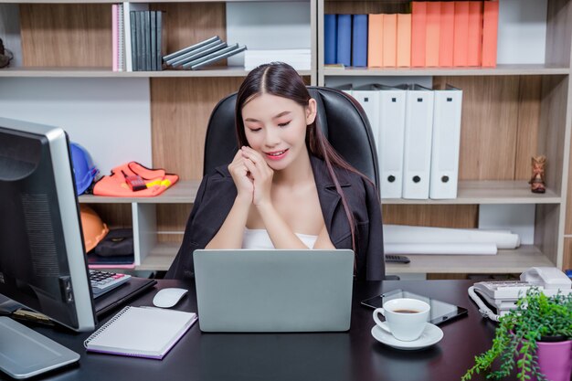Femme d'affaires travaillant au bureau avec un sourire en position assise.