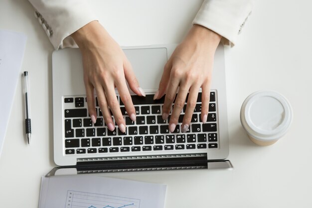 Femme d&#39;affaires travaillant sur un ordinateur portable, mains tapant sur le clavier, vue de dessus