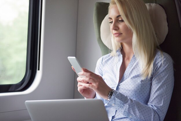 Femme d'affaires travaillant par des appareils mobiles pendant le voyage