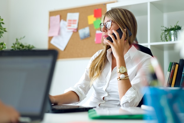 Femme d&#39;affaires travaillant avec un téléphone portable dans son bureau.