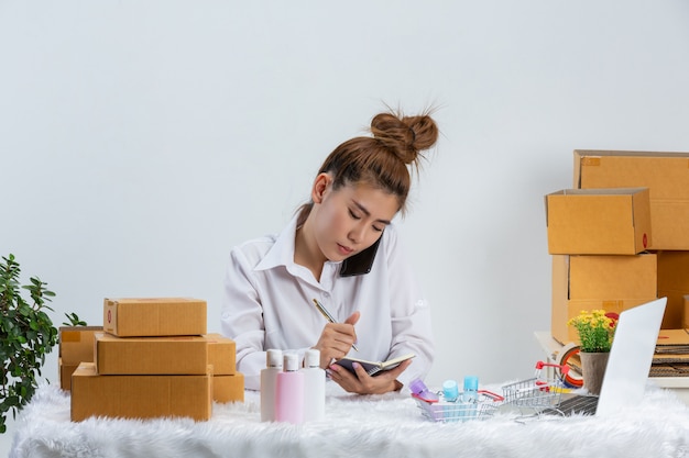 Une Femme D'affaires Travaille En Ligne Et Cherche à Répondre Au Client à L'emballage Du Bureau à Domicile Sur Le Mur.