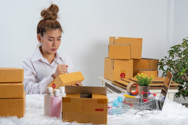 Une femme d'affaires travaille en ligne et cherche à répondre au client à l'emballage du bureau à domicile sur le mur.