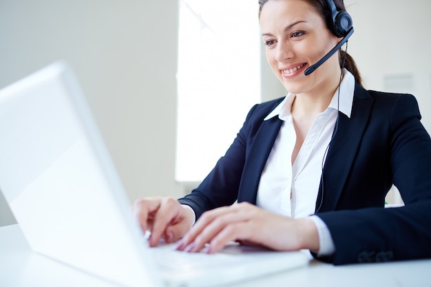 Femme d&#39;affaires en utilisant un casque et un ordinateur portable