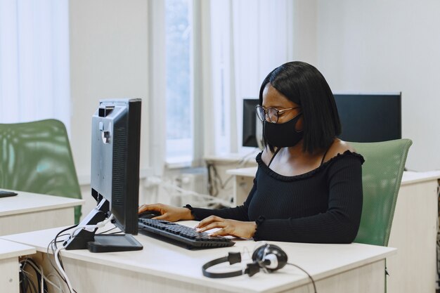 Femme africaine assise en classe d'informatique. Dame à lunettes. Étudiante assise à l'ordinateur.