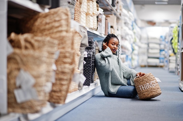 Femme africaine choisissant un panier avec des choses pour son appartement dans un magasin d'ameublement moderne