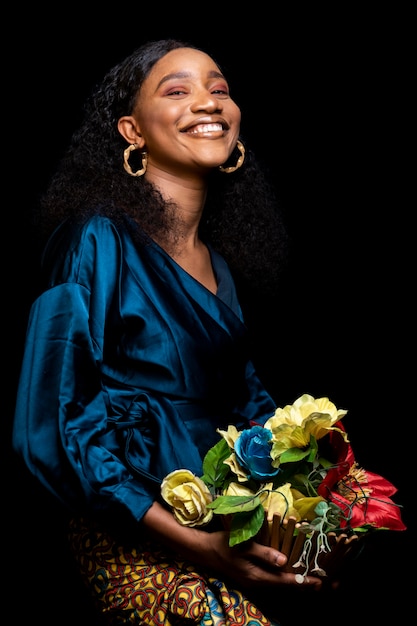 Femme africaine dans des vêtements élégants tenant un bouquet de fleurs