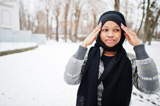 Une femme africaine porte une écharpe noire pose en journée d'hiver en Europe