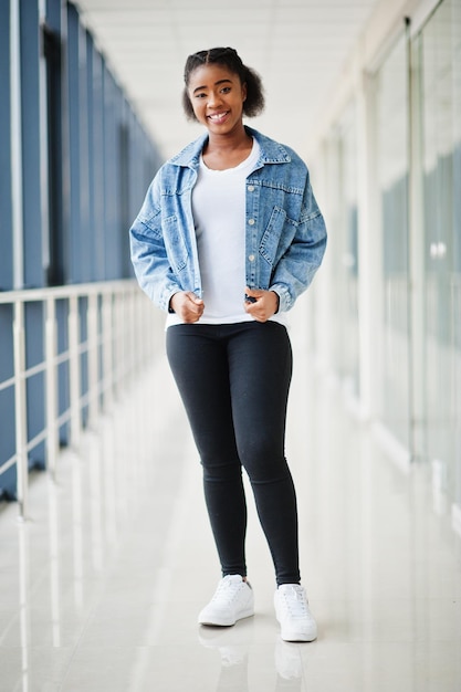 Femme africaine en veste de jeans posée à l'intérieur