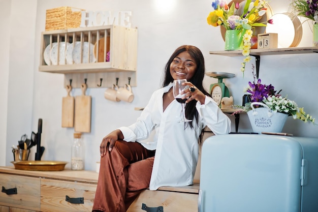 Femme afro-américaine buvant du vin dans la cuisine à son rendez-vous romantique