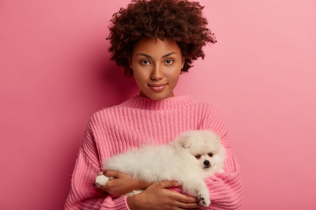 Une femme afro-américaine confiante tient un petit chien, venez chez le vétérinaire pour obtenir des conseils sur la façon de nourrir le spitz de Poméranie