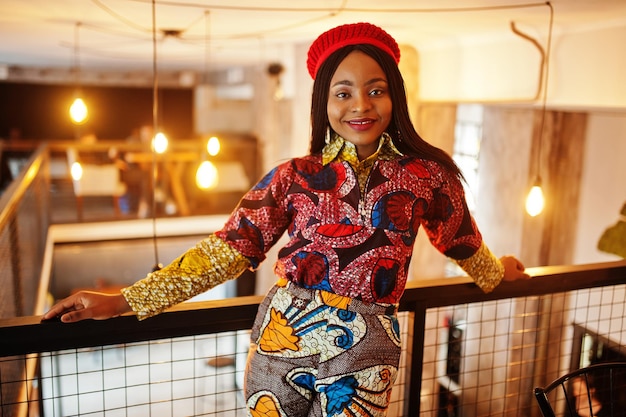 Photo gratuite femme afro-américaine enthousiaste dans une tenue colorée à la mode avec un béret rouge se relaxant dans un café confortable