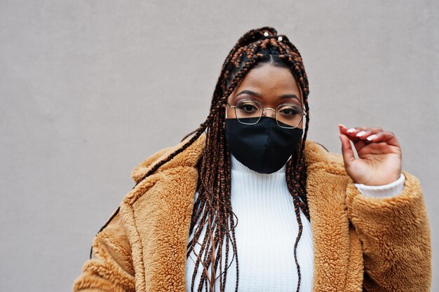 Femme afro-américaine glamour en manteau de fourrure chaud et masque noir