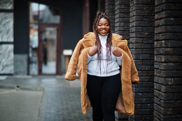 Femme afro-américaine glamour en manteau de fourrure chaud pose dans la rue