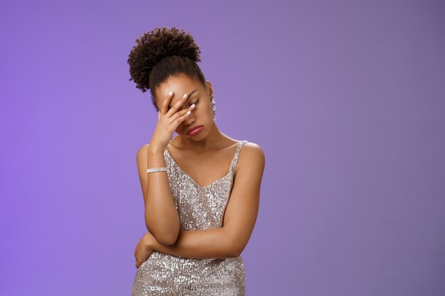 Une femme afro-américaine irritée arrogante, fatiguée, ennuyée, les paumes du visage tiennent les yeux fermés en pinçant les lèvres et...