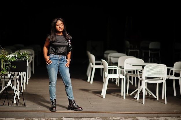 Une femme afro-américaine à la mode porte des jeans posant en plein air