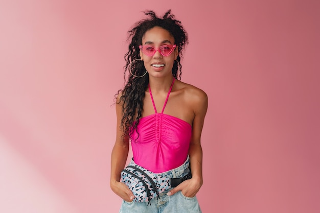 femme afro-américaine noire en tenue d'été élégante haut rose et sac banane short sur rose