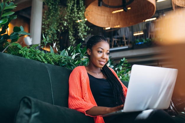 Femme afro-américaine avec ordinateur portable dans un café