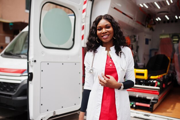 Femme afro-américaine paramédicale debout devant la voiture d'ambulance