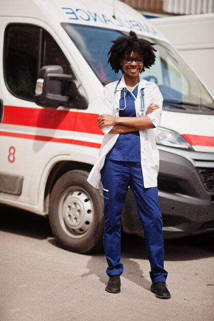 Femme afro-américaine paramédicale debout devant la voiture d'ambulance