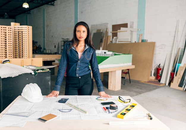 Femme afro-américaine près de la table avec casque et équipements de sécurité