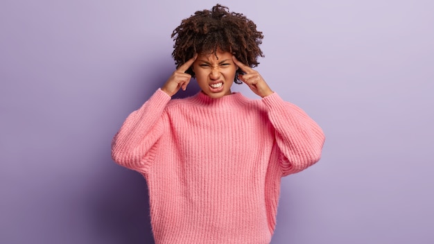 Photo gratuite une femme afro-américaine souffre de migraine, touche les tempes, a besoin d'analgésiques, serre les dents, ne peut pas supporter la douleur