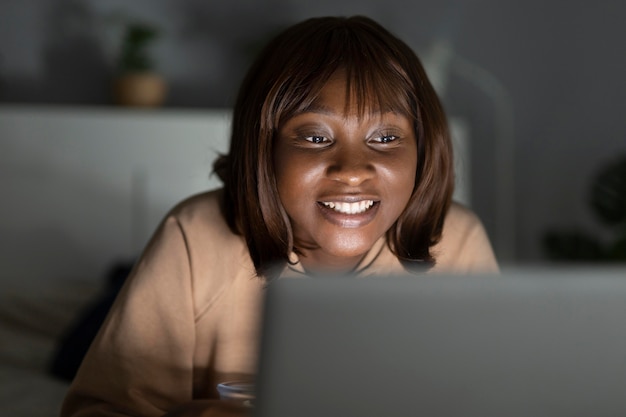 Femme afro-américaine souriante regardant le service de streaming à la maison