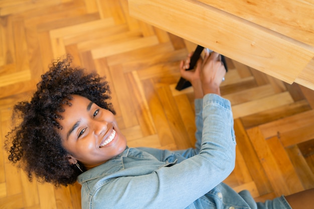 Photo gratuite femme afro réparant des meubles à la maison.