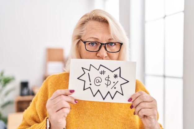 Une femme d'âge moyen, blonde, travailleuse d'affaires, tenant une bannière avec un message de tir au bureau.