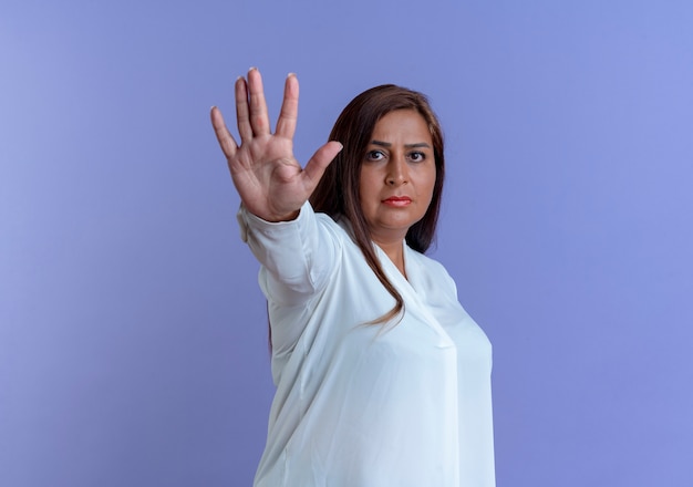 Femme d'âge moyen caucasienne occasionnelle stricte montrant le geste d'arrêt isolé sur le mur bleu