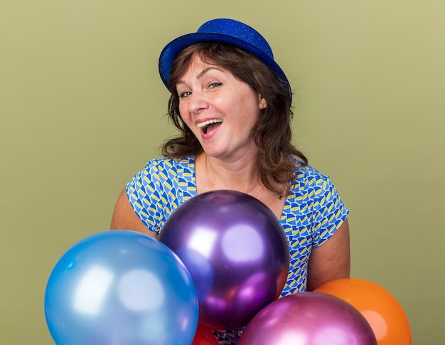 Femme D'âge Moyen Heureuse Et Excitée En Chapeau De Fête Avec Un Tas De Ballons Colorés S'amusant