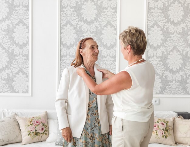 Femme d&#39;âge mûr assistant sa mère en veste à la maison