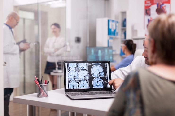 Photo gratuit femme âgée au bureau de l'hôpital regardant un scanner cérébral tout en discutant avec un médecin du diagnostic. jeune femme malade et infirmier âgé aux cheveux gris dans le couloir de la clinique.