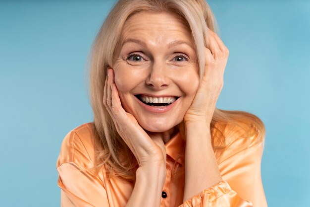 Femme âgée blonde riant sur un fond bleu