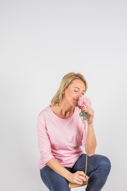 Femme âgée en blouse rose sentant la floraison